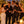 EUPHORIA – The Contender lacht mit Freunden auf einer Dachterrasse am Abend.